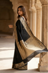 Woman wearing a black and gold saree in an architectural setting
