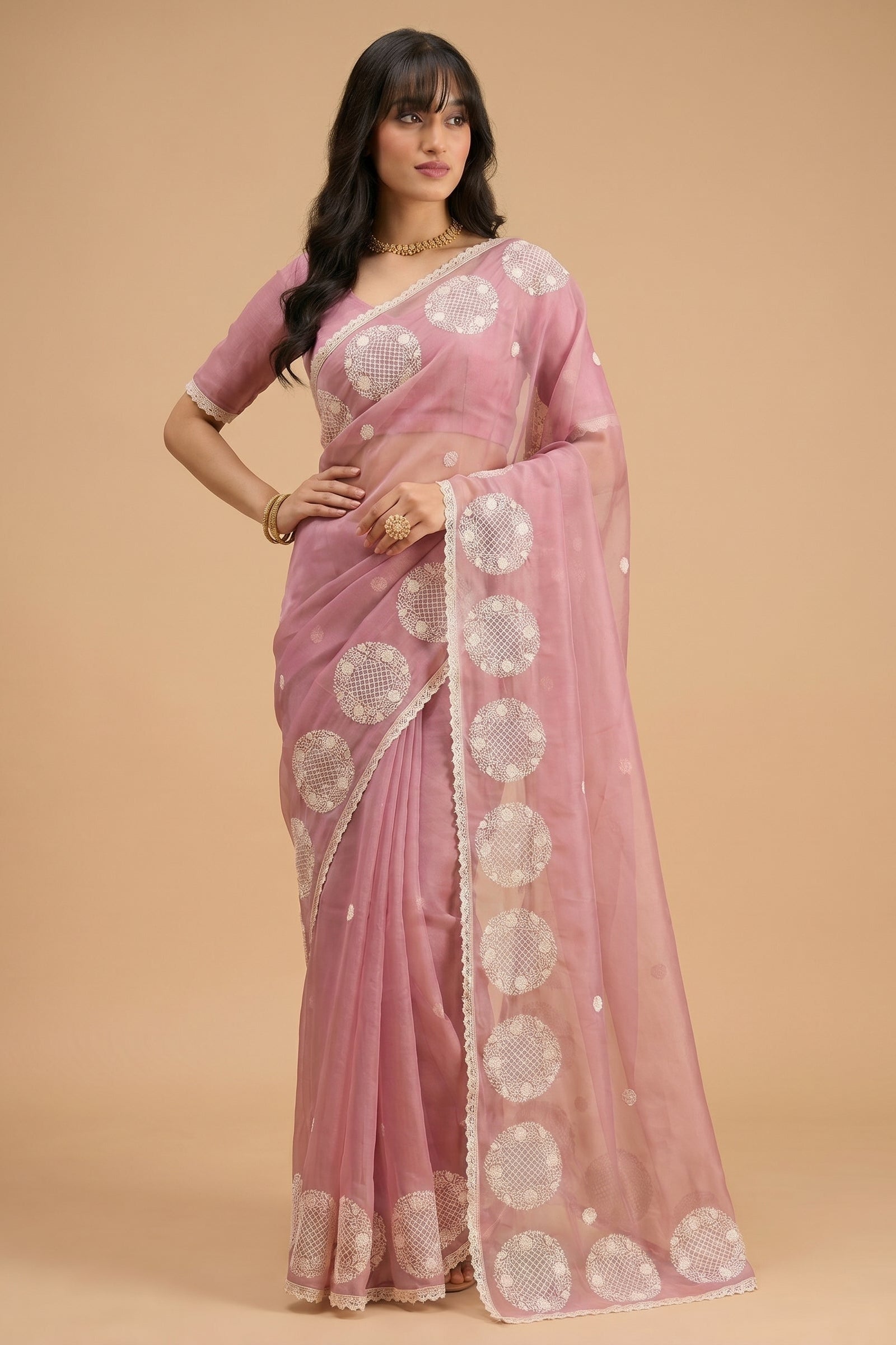 Woman wearing a pink saree with white patterns on a beige background