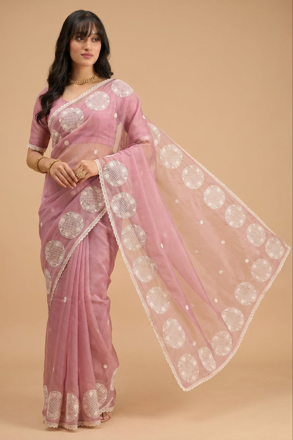 Woman wearing a pink saree with white patterns on a beige background