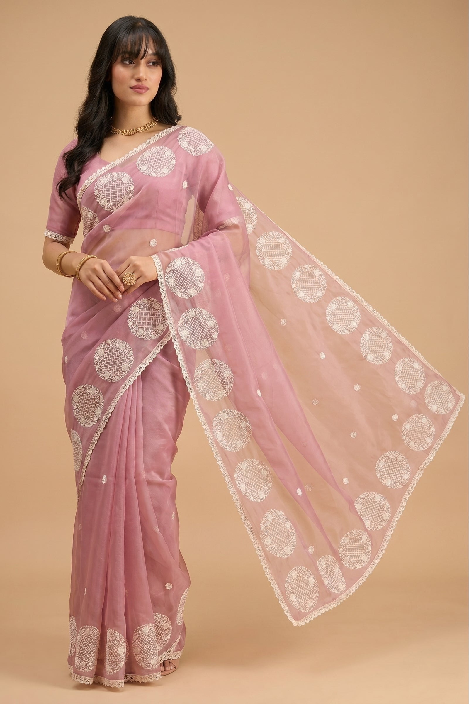 Woman wearing a pink saree with white patterns on a beige background