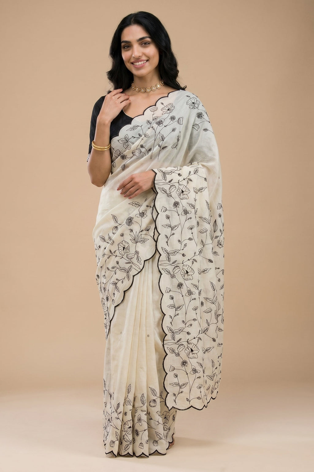 Woman wearing a white saree with black floral patterns on a beige background