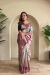 Woman in a Mauve and white saree standing indoors with plants in the background
