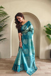 Woman wearing a blue saree with white patterns indoors. Tea Green