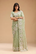 Woman wearing a light green saree with a beige background