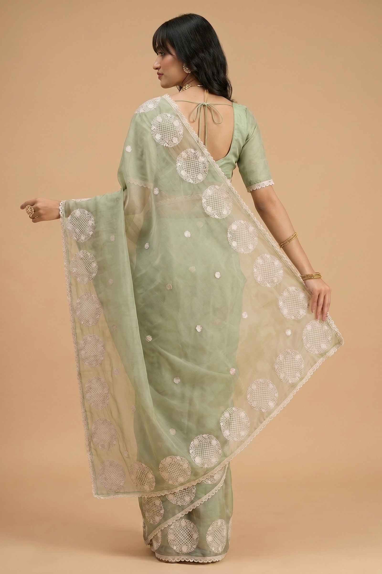 Woman wearing a light green saree with a beige background