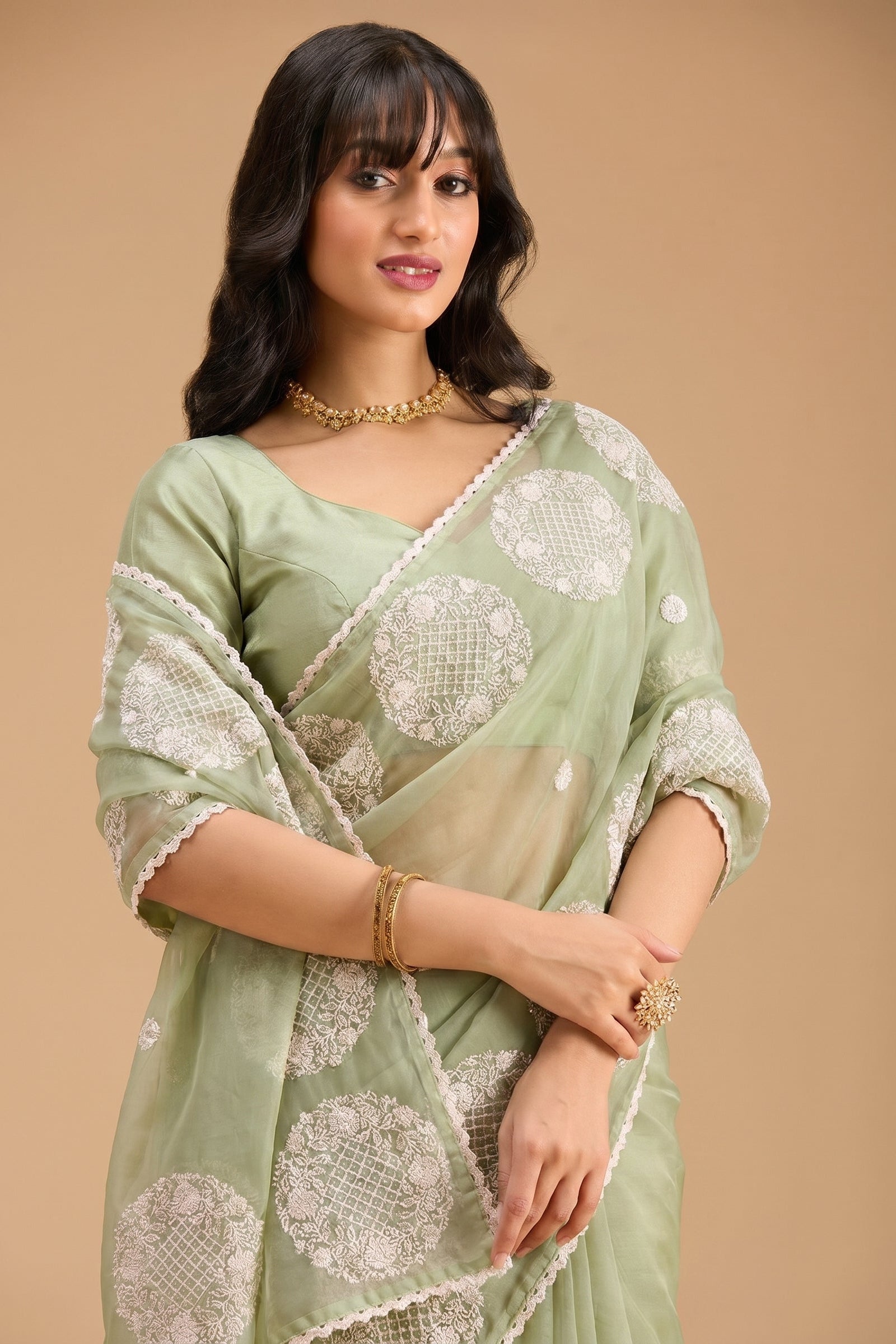 Woman wearing a light green saree with white patterns on a beige background