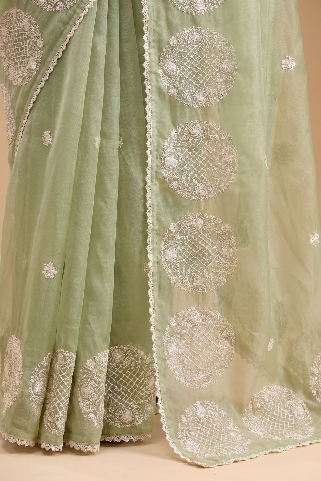 Light green saree with intricate white embroidery on a beige background
