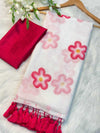 White scarf with pink floral patterns and red tassels on a white surface.